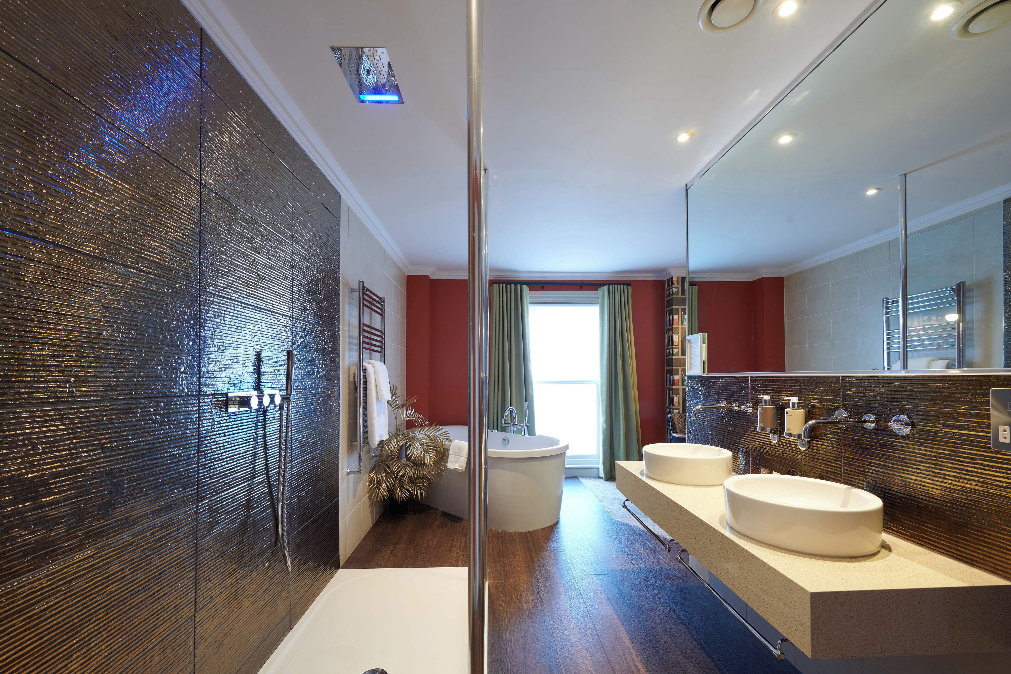 A modern bathroom with a glass shower enclosure, a bathtub, and two sinks.