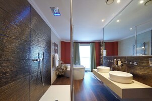 A modern bathroom with a glass shower enclosure, a bathtub, and two sinks.