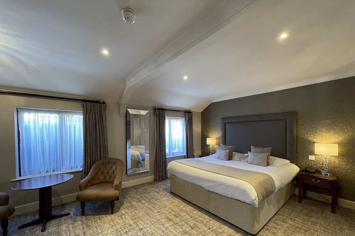 Een hotelkamer met een groot bed, een ronde tafel, een stoel en een spiegel.