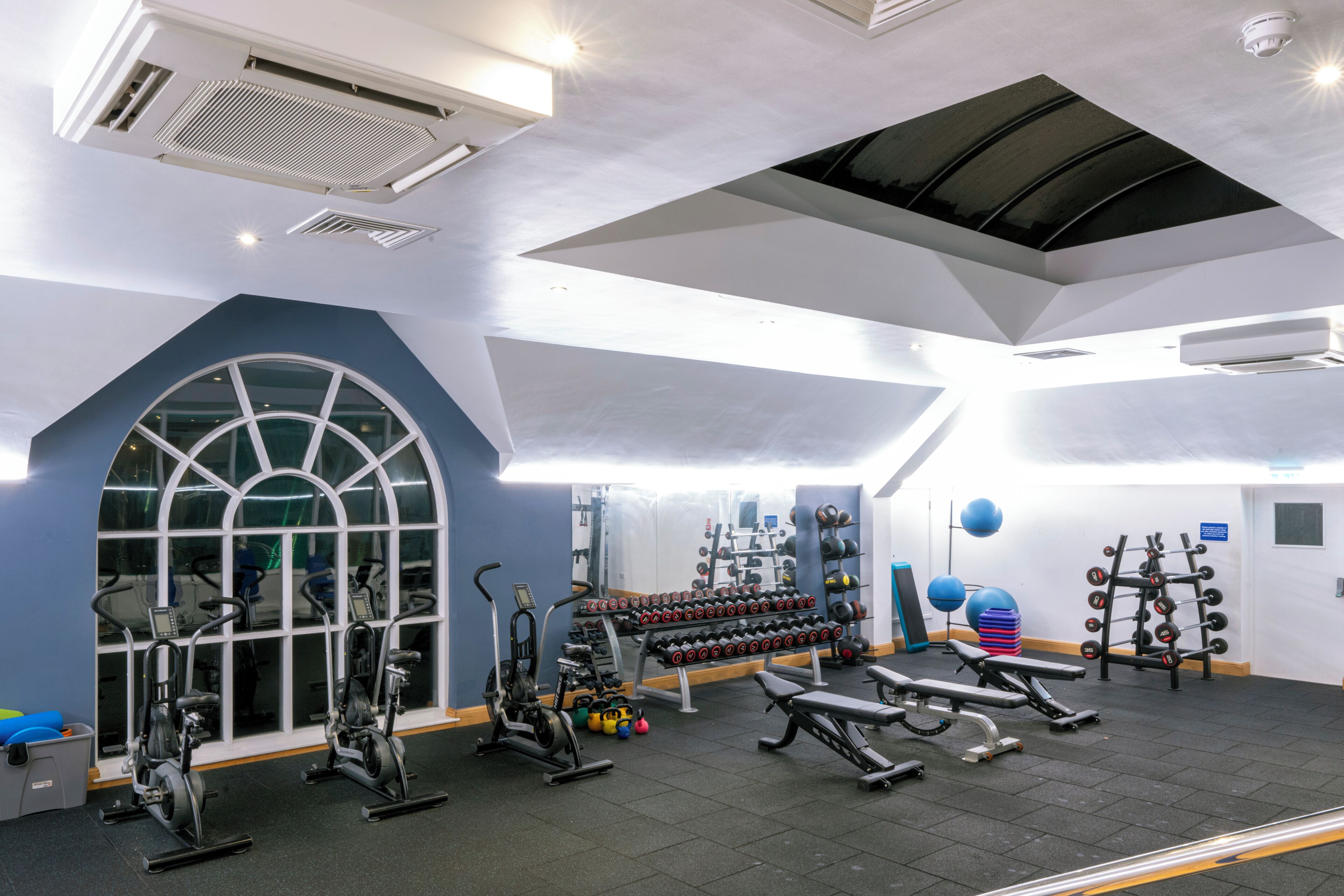 A gym with exercise equipment, a large window, and a ceiling with a skylight.