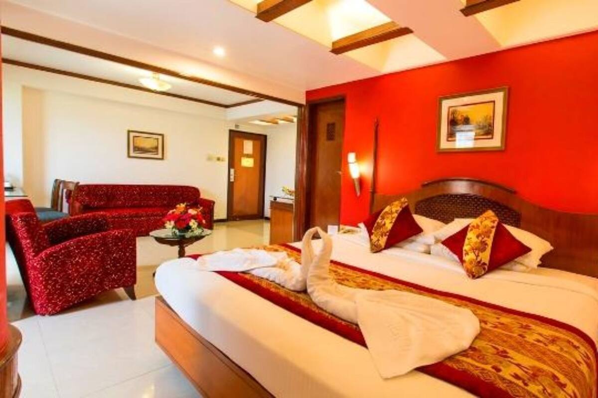 Una habitación de hotel con una cama grande, una pared roja y un cabecero de madera.