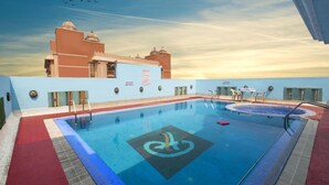 En swimmingpool med en hoppställning, omgiven av en röd matta, och en byggnad med kupolformade tak i bakgrunden.