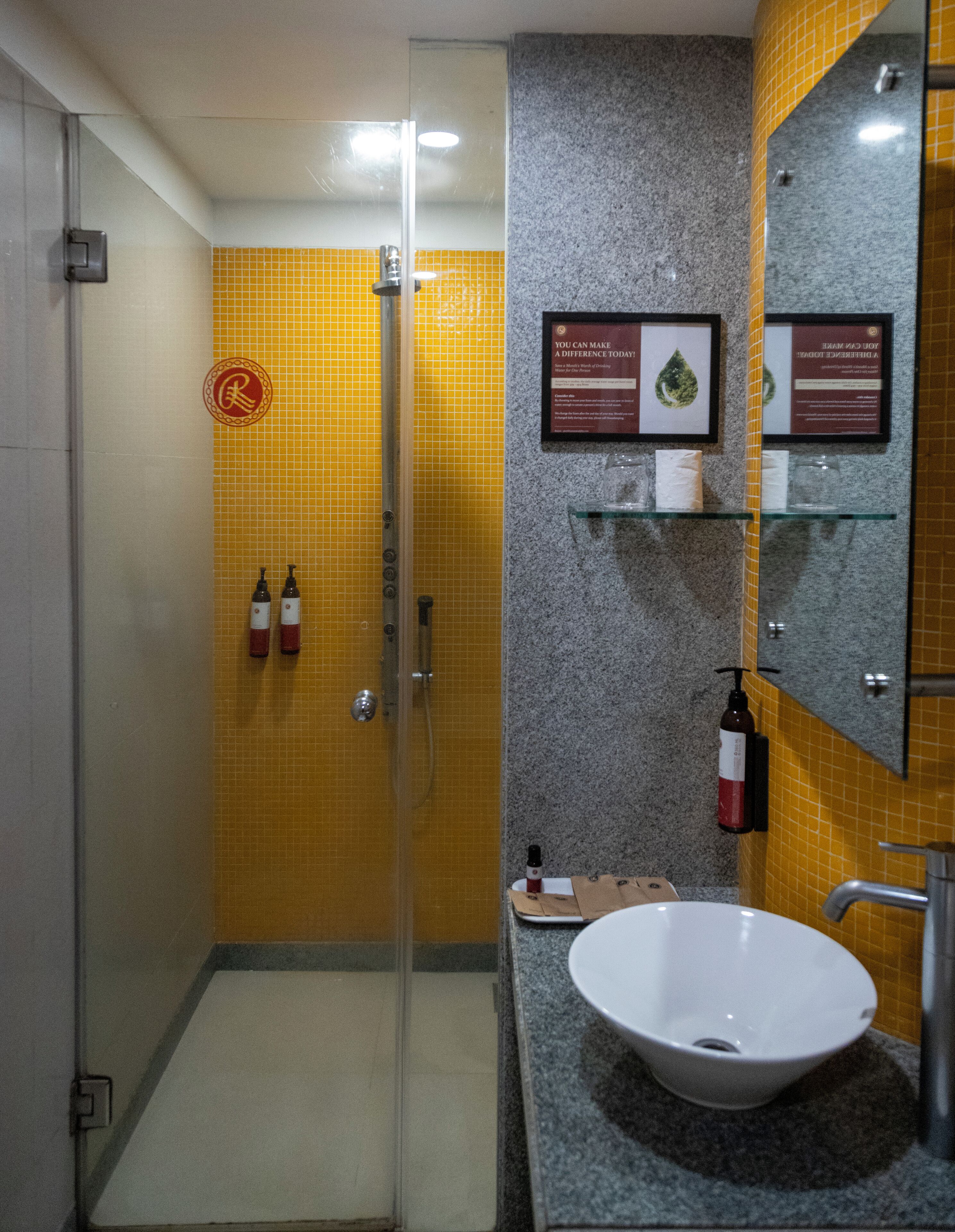 A bathroom with a glass shower enclosure, a sink with a marble countertop, and a mirror above the sink.