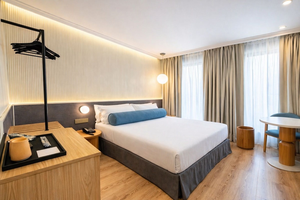 Ein Hotelzimmer mit Bett, Nachttisch, Lampe und Blick ins Freie.