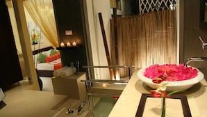 Un baño moderno con un espejo grande, un jarrón de flores rosas y un perchero para toallas.