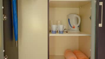 A walk-in closet with shelves, a hanging rack, and a kettle.