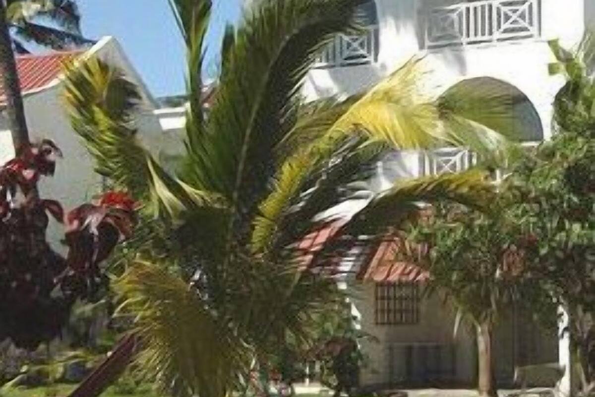 Un bâtiment blanc avec un toit rouge, entouré de palmiers et de verdure.