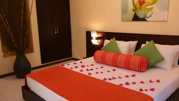 A hotel room with a bed, pillows, a vase, and a wall-mounted lamp.