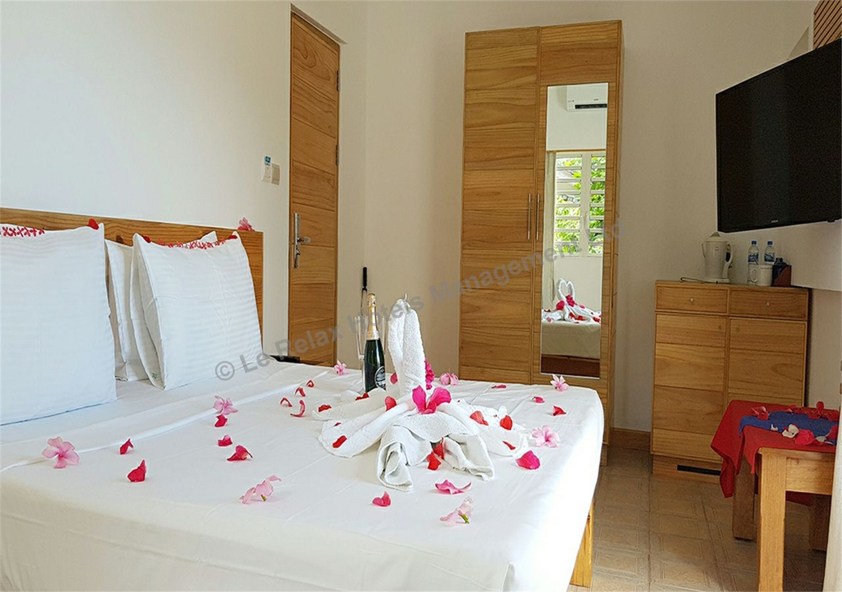 Une chambre d’hôtel avec un lit, une armoire en bois, une télévision et une petite table.