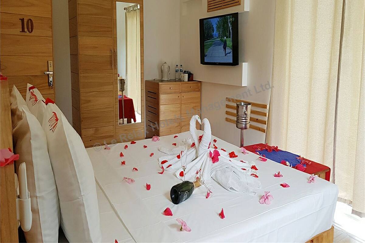A hotel room with a bed, a wooden dresser, a television, and a door marked with the number 10.