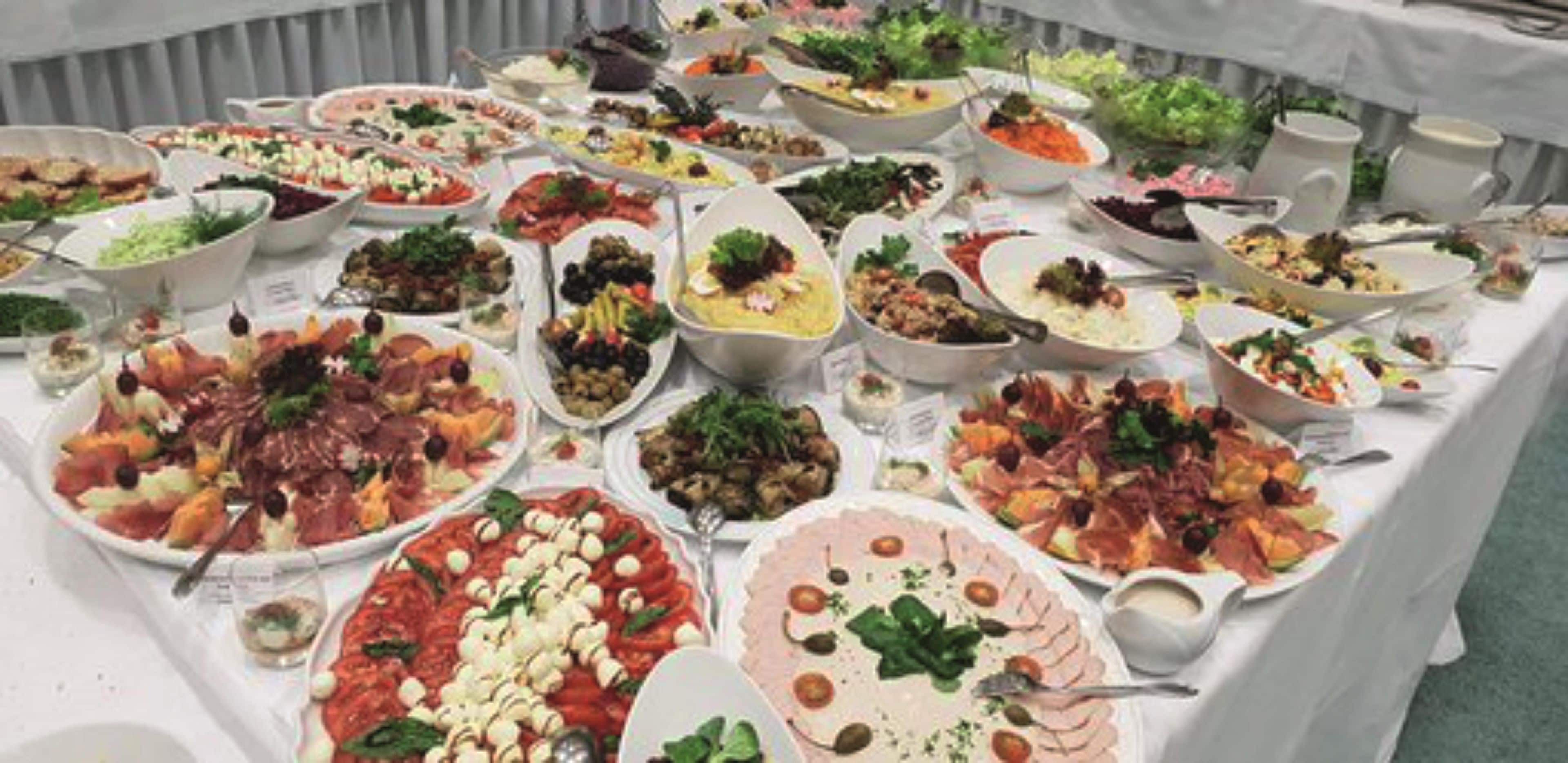 Taula de buffet amb diferents plats i un llençol blanc.