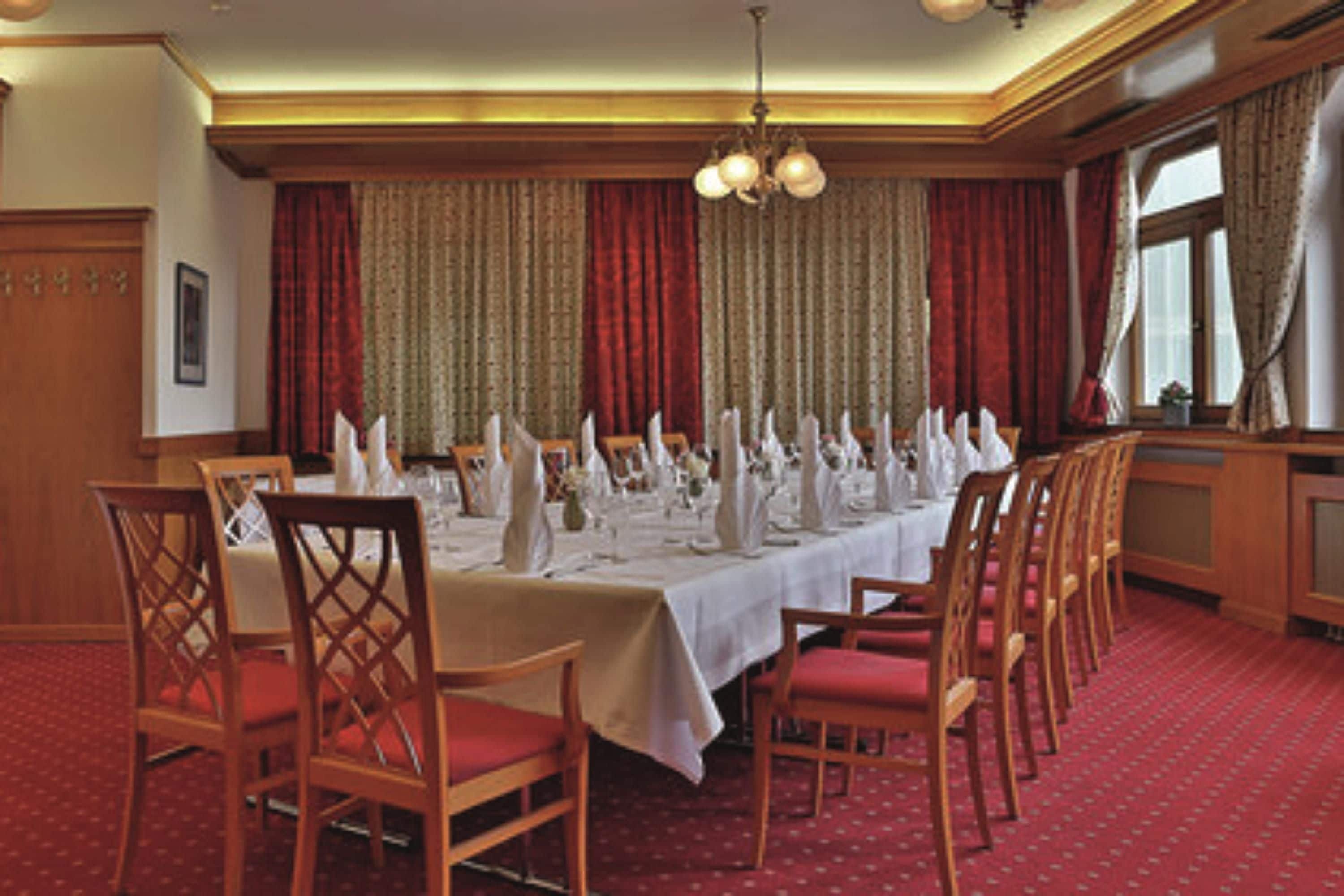 Een elegante eetzaal met een lange tafel, gedekt voor een maaltijd, omringd door houten stoelen.