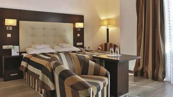 A hotel room with a large bed, a desk, and a chair. There are two bedside tables with lamps.
