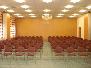 A conference room with rows of red chairs, a chandelier, and a wooden wall with a logo. - Hotel Empfinger Hof, Sure Hotel Collection by Best Western (Empfingen)
