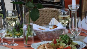 A dining table set with plates of food, glasses of white wine, and a basket with bread. - Hotel Empfinger Hof, Sure Hotel Collection by Best Western (Empfingen)