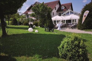 A grassy outdoor area with a white tent and tables, surrounded by trees and a building with a red roof. - Hotel Empfinger Hof, Sure Hotel Collection by Best Western (Empfingen)