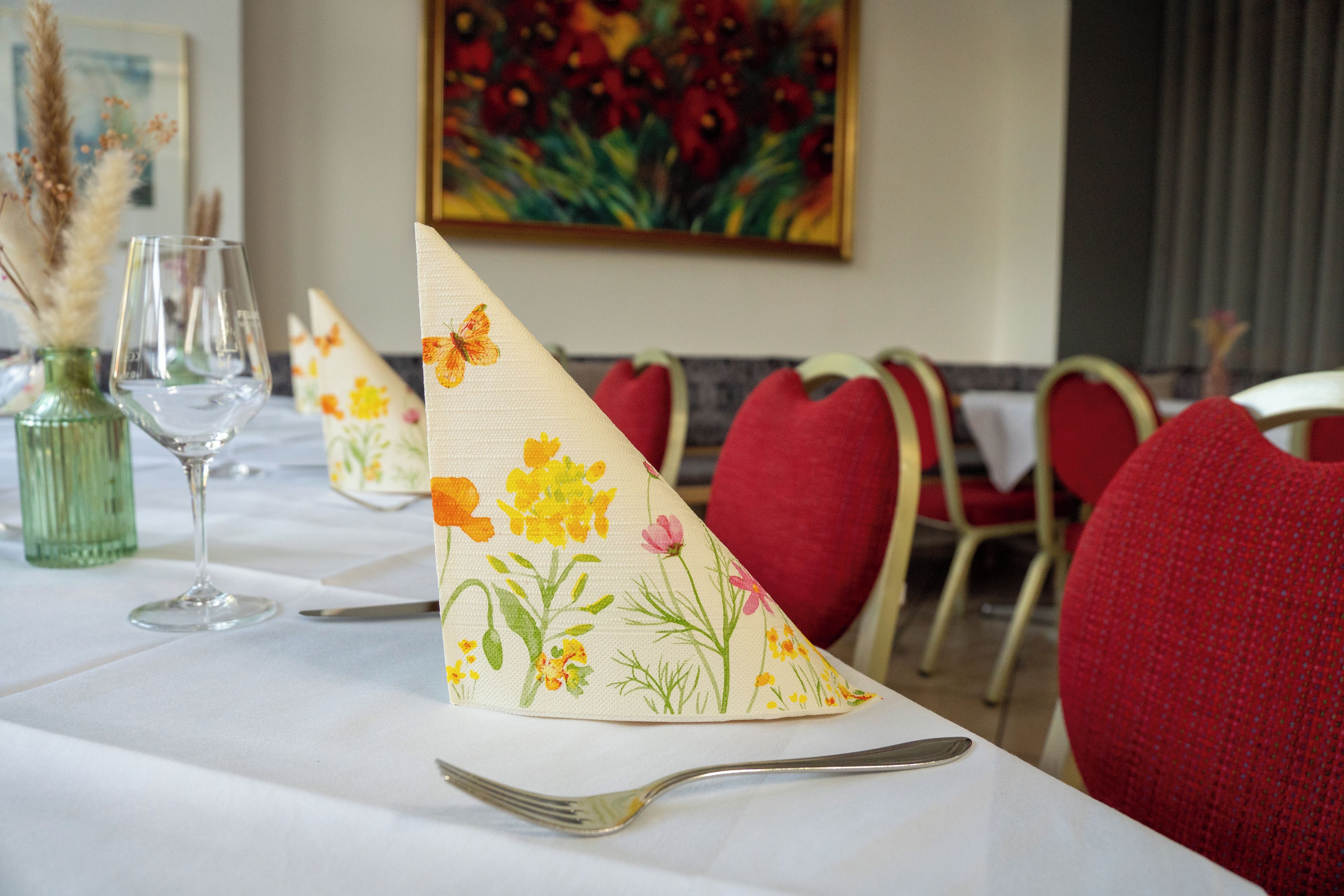 A dining table set with a white tablecloth, red chairs, and a silver fork.