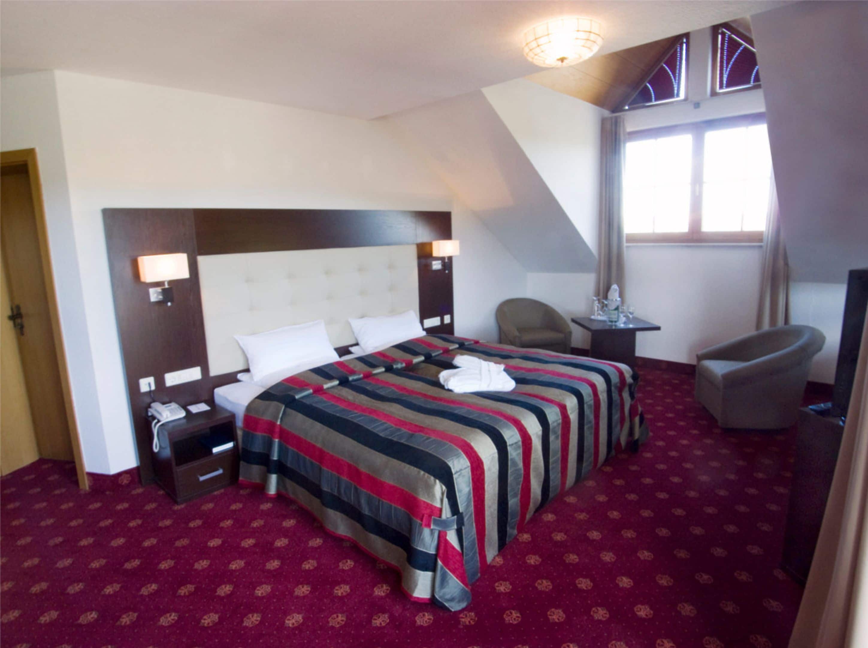 Habitación de hotel con una cama grande, un escritorio, una silla y una ventana.