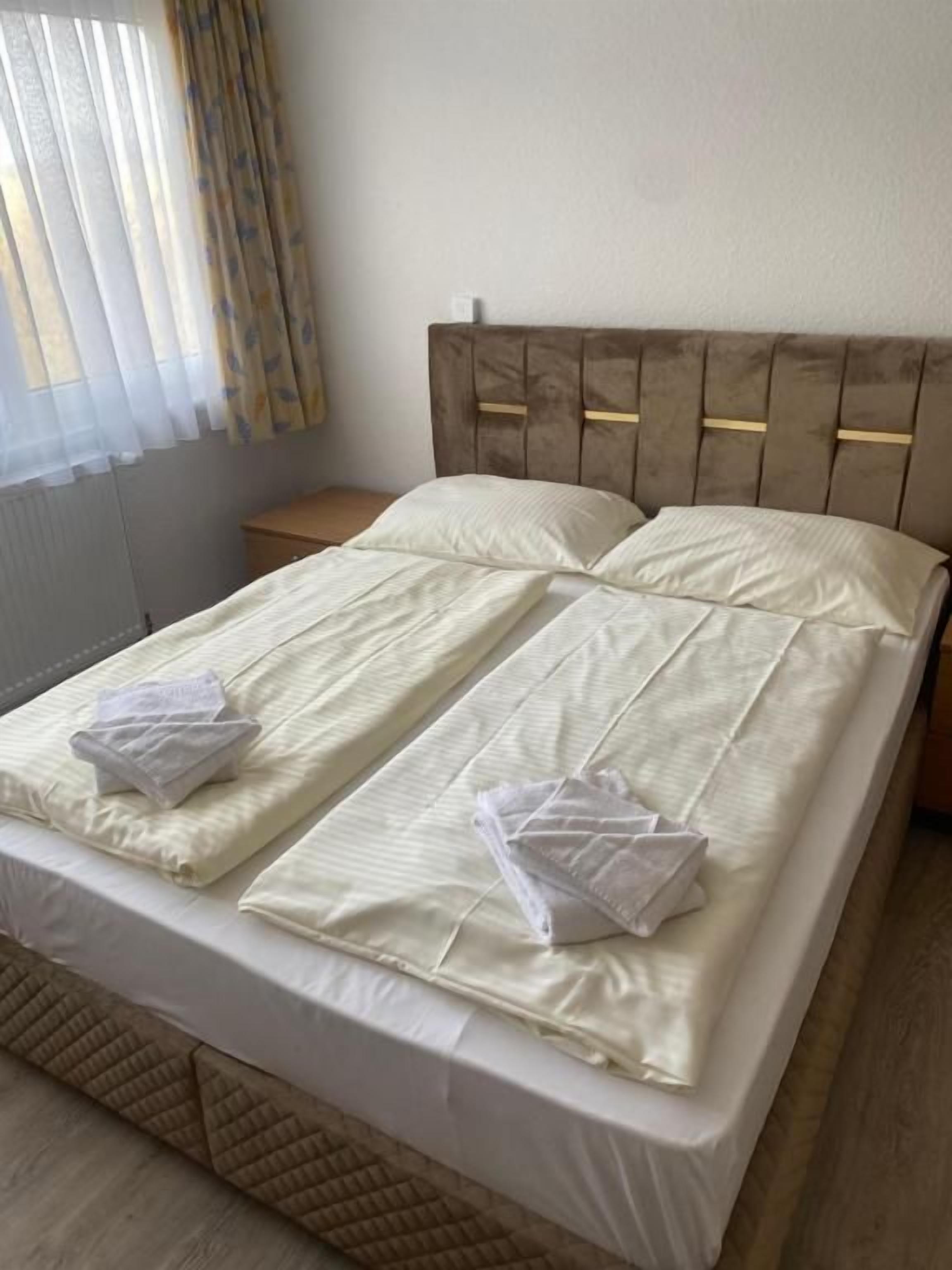 A double bed with a wooden headboard, two pillows, and a neatly made bedspread.