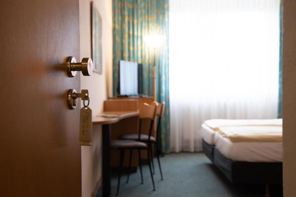 A hotel room with a bed, a desk, and a chair.