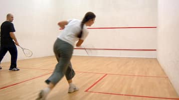 Una palestra per squash con pavimento in legno e linee di delimitazione rosse.