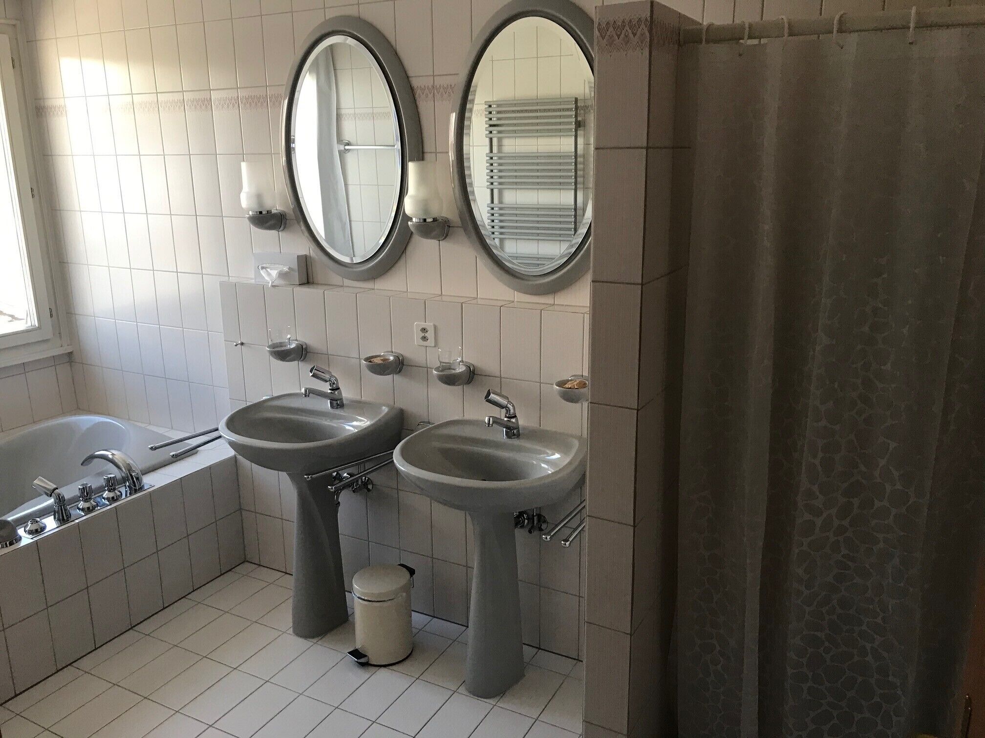 A bathroom with two sinks, a bathtub, and two mirrors.