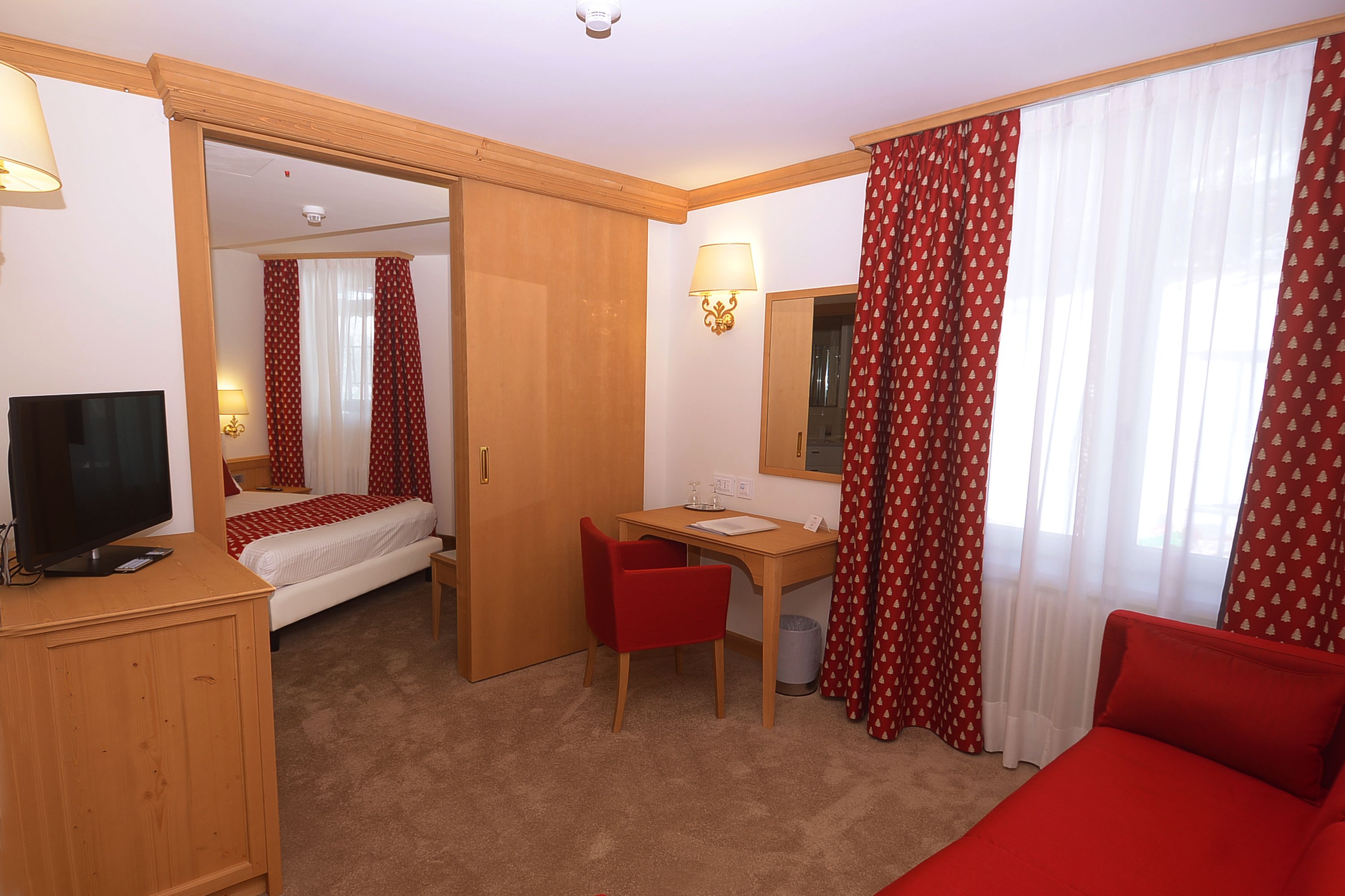 Une chambre d’hôtel équipée d’un lit, d’un bureau, d’une chaise, d’une télévision et d’un miroir.