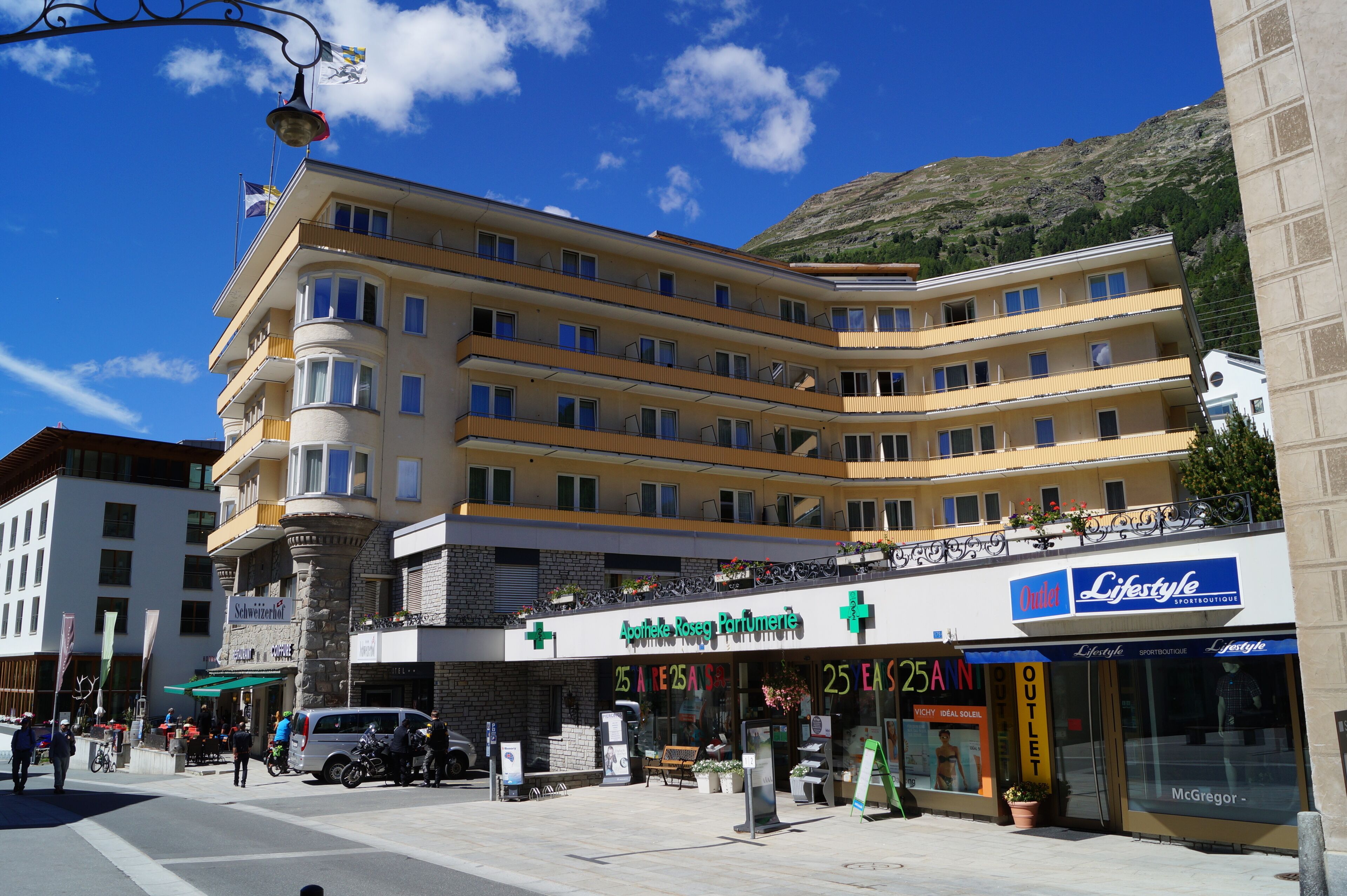 A multi-story hotel with a stone facade, balconies, and a sign for 'Apostle Roseg Parumere'.
