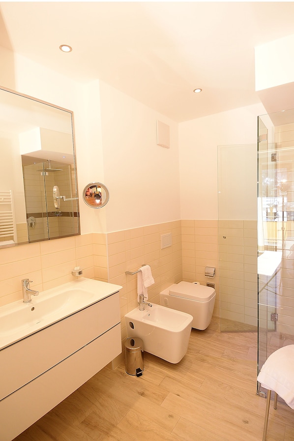 A modern bathroom with a large mirror, two sinks, a shower, and a glass-enclosed shower area. - Schweizerhof Pontresina (Pontresina)