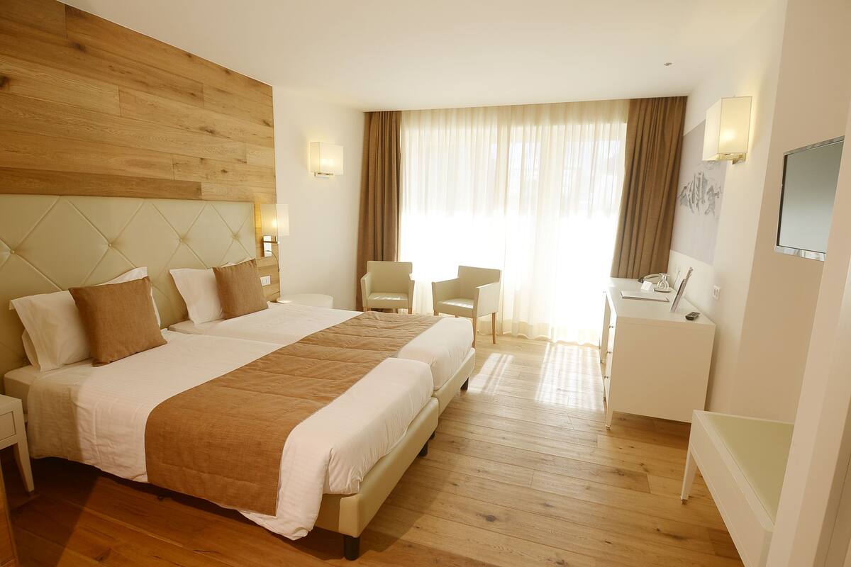 Une chambre d’hôtel avec un grand lit, un bureau, une chaise et un téléviseur.