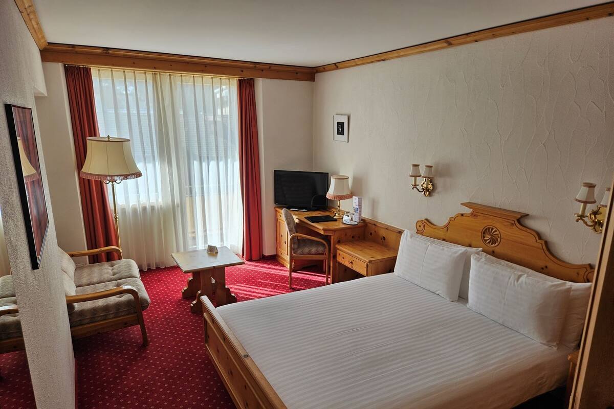Une chambre d’hôtel avec un grand lit, un bureau avec un ordinateur, une chaise et un téléviseur.