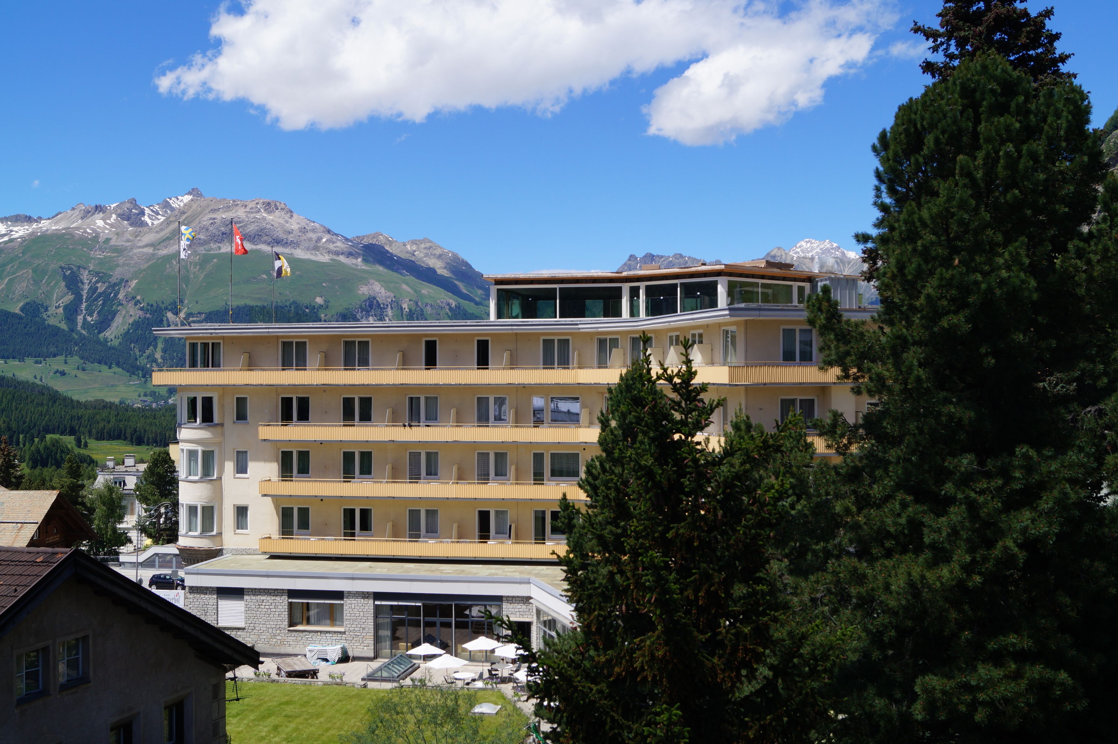 Un hotel de varios pisos con balcones, vista a la montaña y cielo despejado.