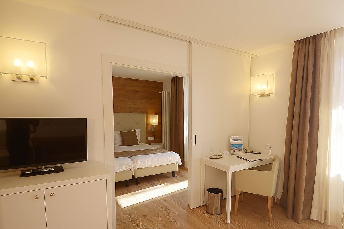 Une chambre d’hôtel équipée d’un lit, d’un bureau, d’une télévision et d  ’une poubelle.