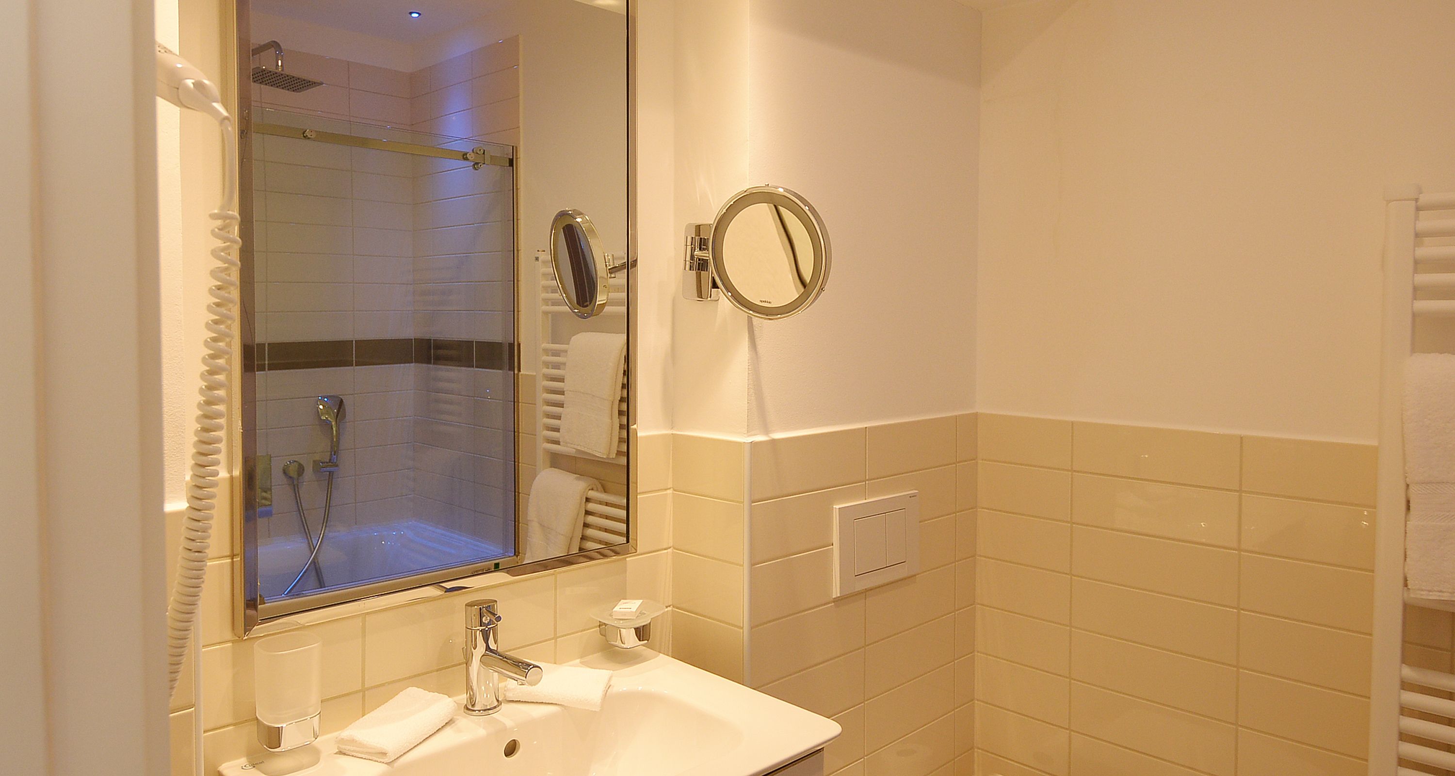 Un baño con lavamanos, espejo y ducha.