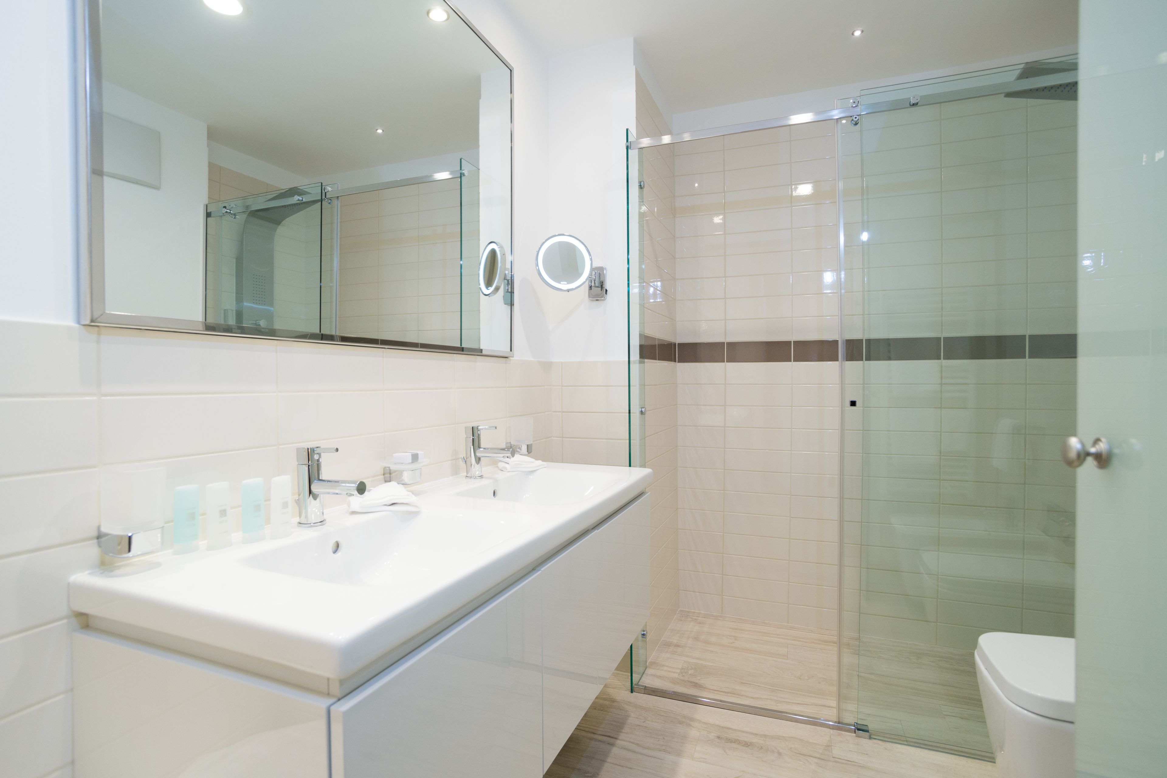 A modern bathroom with a glass-enclosed shower, a large mirror, and a white vanity with a sink.