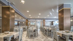 Uma ampla área de jantar com várias mesas e cadeiras, um design de parede estampado e piso de mármore.
