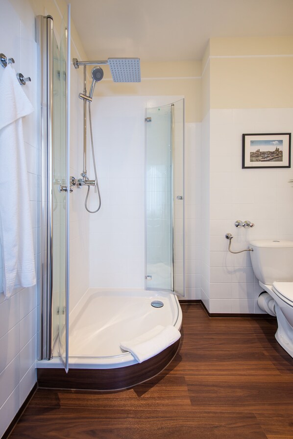 Un bagno moderno con doccia vetrata, un water bianco e un quadro appeso al muro.