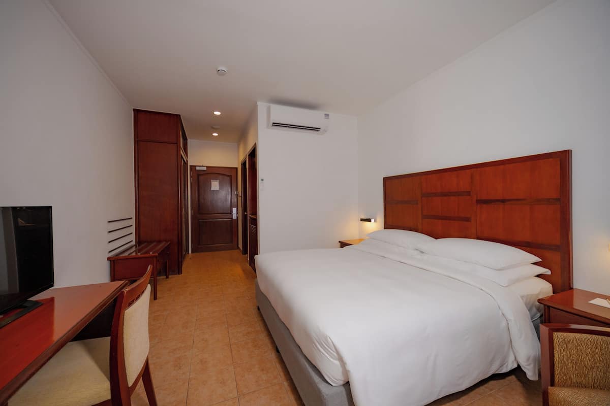 Ein Hotelzimmer mit Bett, Schreibtisch, Stuhl, Fernseher und Kleiderschrank.