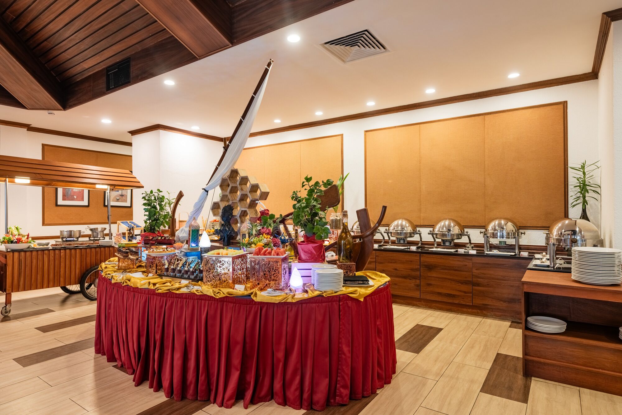 A buffet setup with a variety of food items, a decorative centerpiece, and a wooden panel wall in the background.