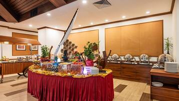 A buffet setup with a variety of food items, a decorative centerpiece, and a wooden panel wall in the background.