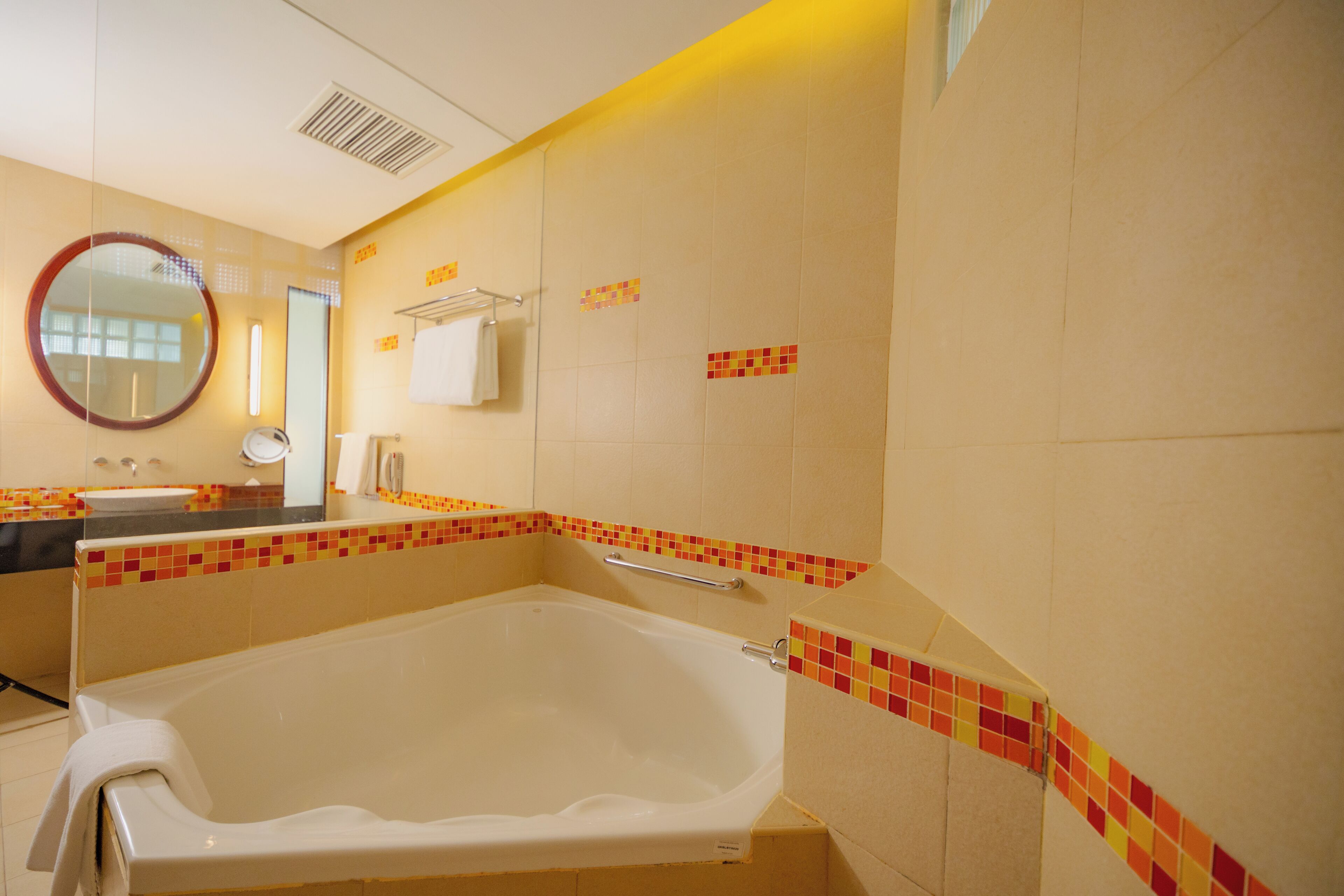 A bathroom with a bathtub, a mirror, a towel rack, and a sink.