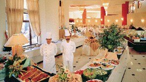 A buffet setup with chefs, a variety of dishes, and a formal dining area with tables and chairs. - Palazzo di Zante (Zakynthos)