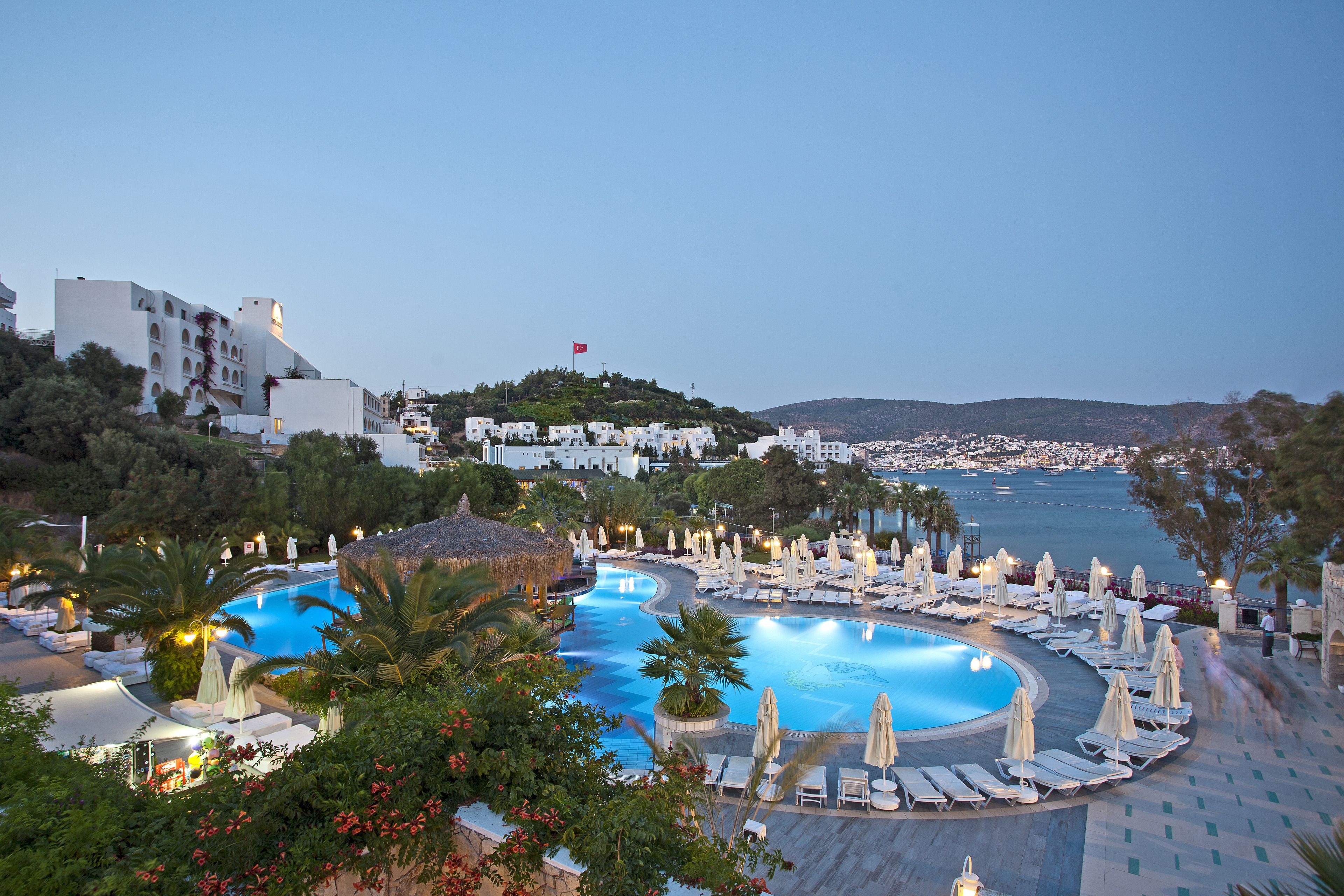 Un resort con una amplia piscina, tumbonas y vistas al mar.