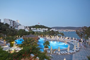 Un resort con una amplia piscina, tumbonas y vistas al mar.