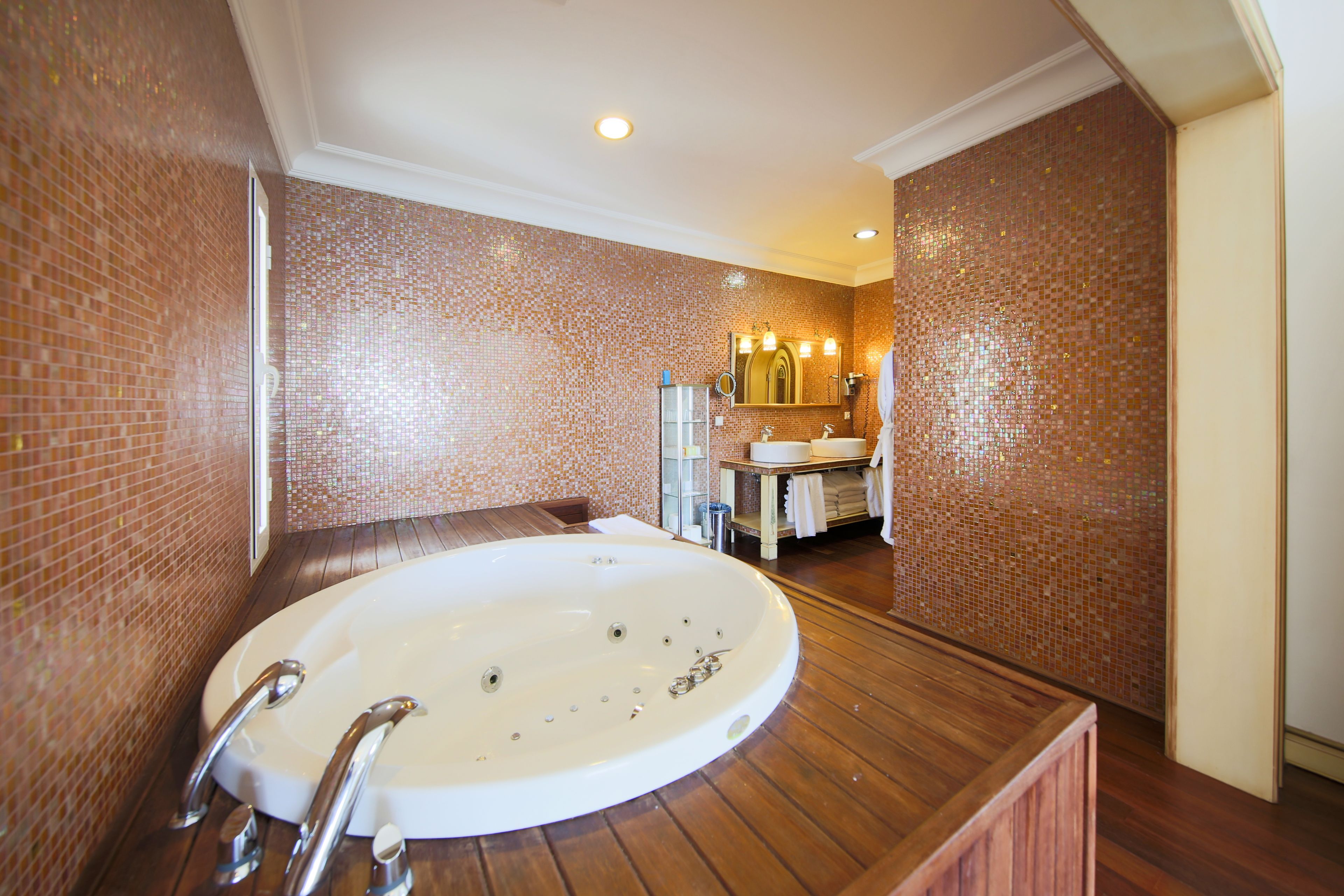 A bathroom with a large bathtub, a sink, and a mirror.
