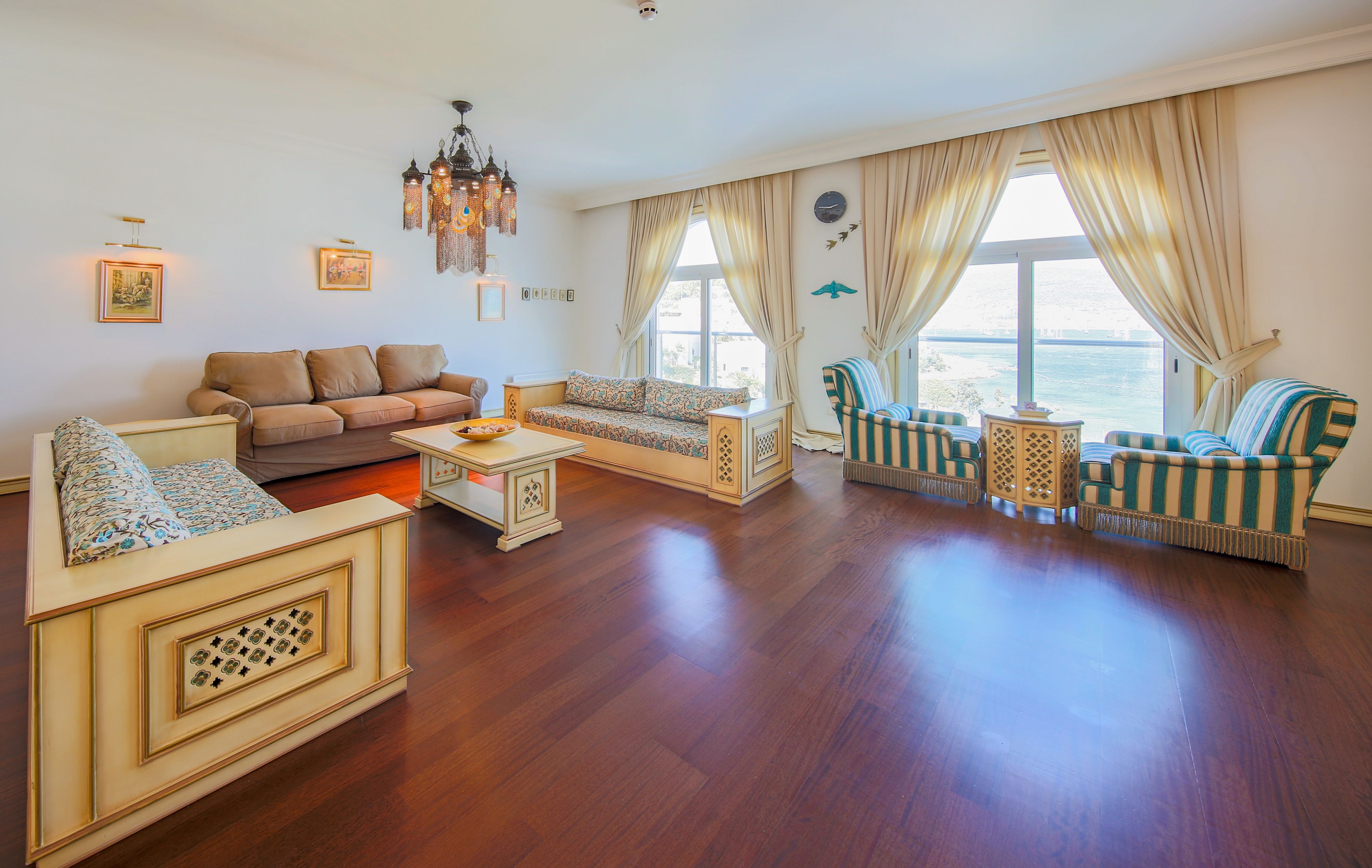 A spacious living room with a sofa set, a patterned armchair, and a small table.