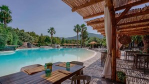 A poolside area with a wooden pergola, outdoor seating, and a view of the pool. - Hotel Il Monastero (Quartu Sant'Elena)