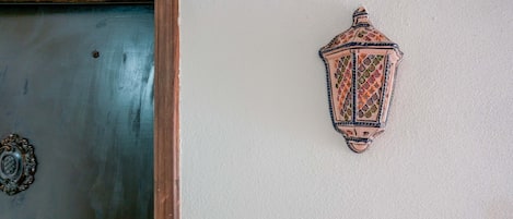 A door with a metal handle and a decorative lantern on the wall.
