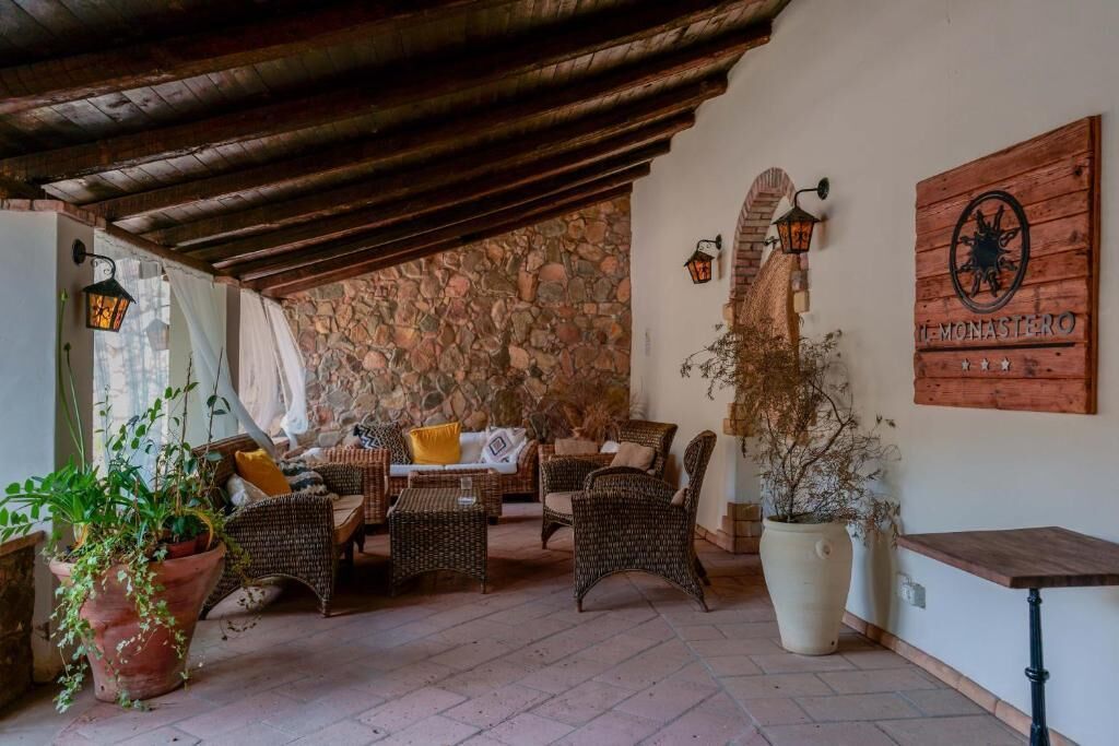 Un espace patio accueillant, avec des meubles en osier, des murs en pierre et un plafond en bois.