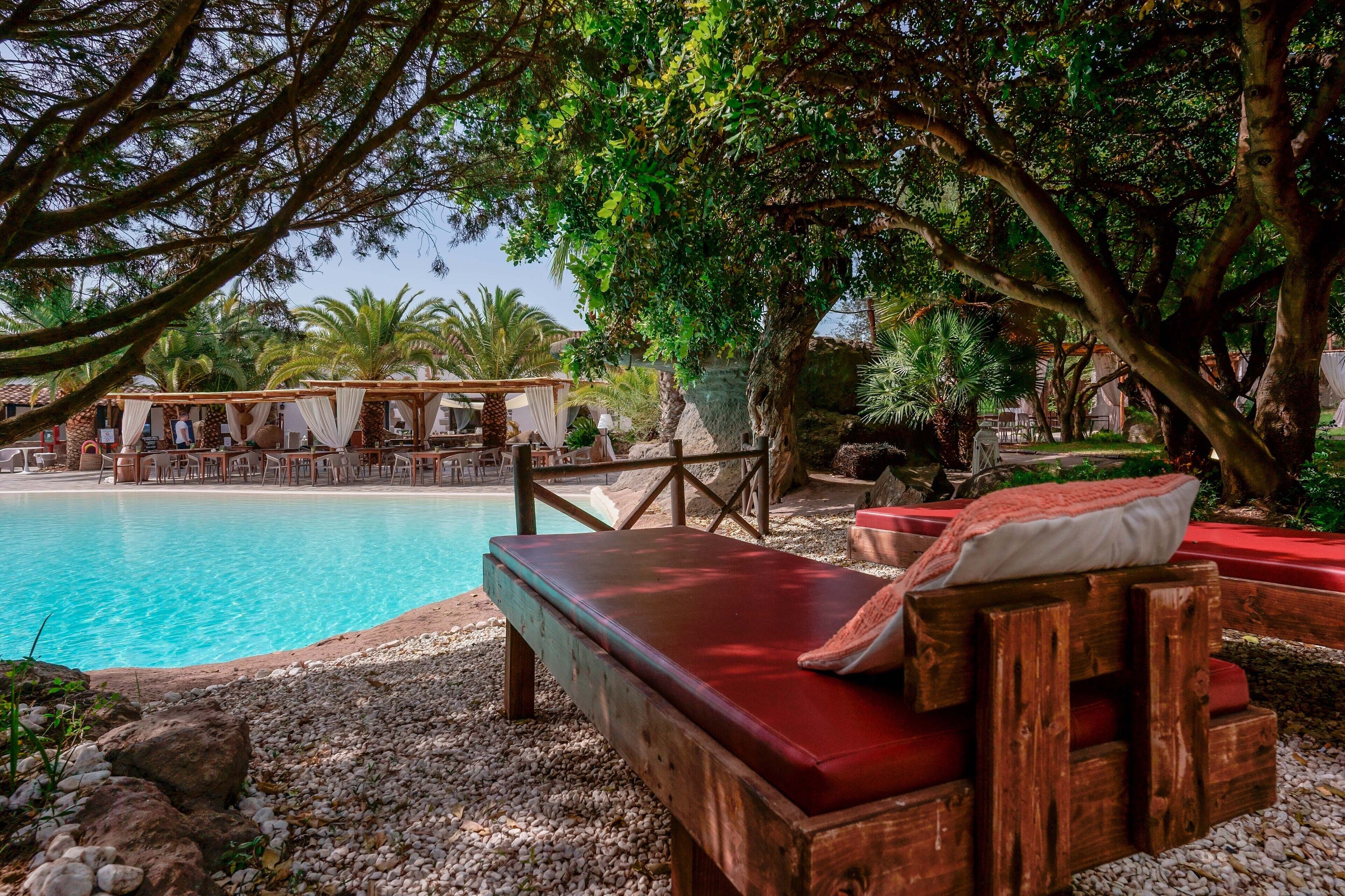 A poolside area with wooden loungers, a covered seating area, and a view of the pool.